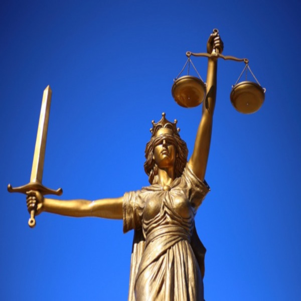 image of golden colored lady justice with blindfold against blue sky